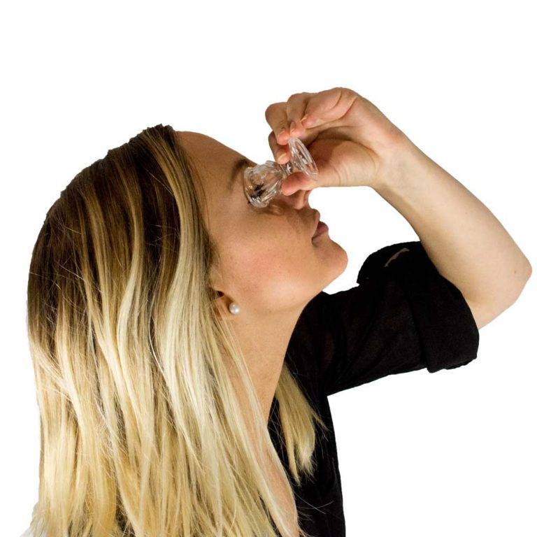 Woman using eye wash cup to clean her right eye.