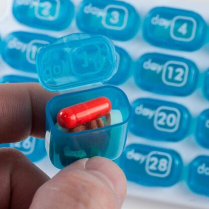 GMS Pop Out 31 Day Pill Organizer Hand Holding one Pop Out Pill Pod Open with Medicine