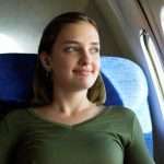a girl wearing pressure reducing ear plugs on a plane