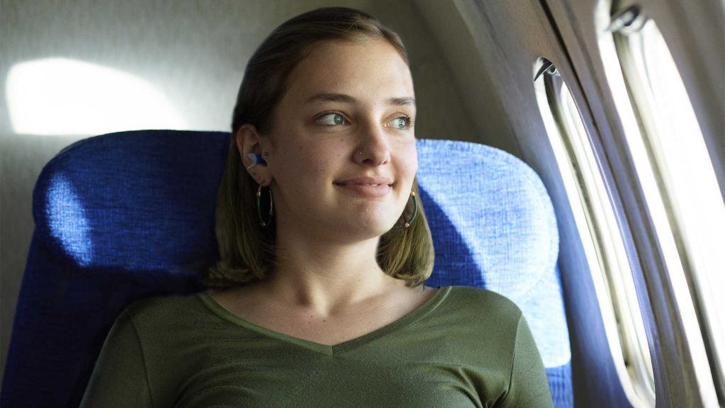 Woman on a plane, wearing earplugs, after going through TSA